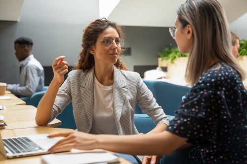 Female caucasian company manager mentor consulting asian client explaining project work to trainee intern instructing new worker at workplace, apprenticeship, advice and internship course concept